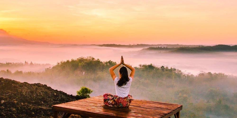 Young white lady doing yoga alone in the forest at sundown, sports played sitting down, sitting down sports, doing sports while sitting, what sports can i do sitting, lazy sports, weird sports, unusual sports, yoga, online sportsbooks, gamingzion